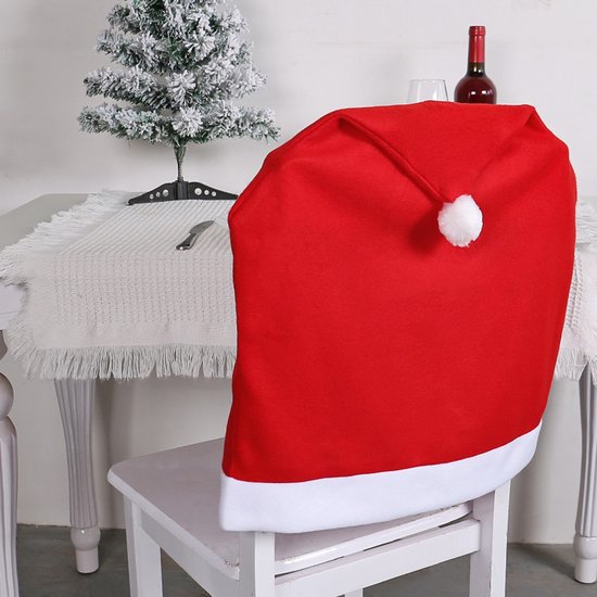 Rode kerstmuts stoelhoes met witte rand en pompon op een witte stoel.