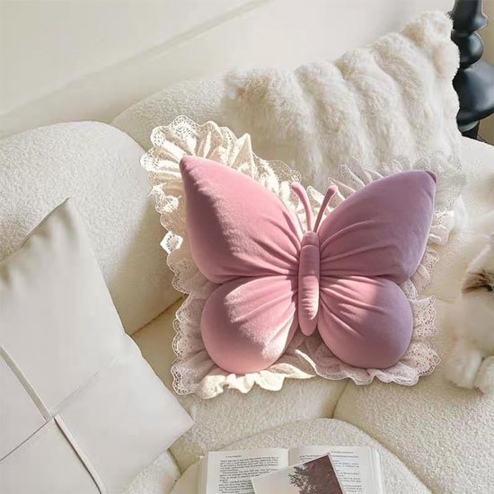 Roze vlinderkussen met kanten rand, op een witte bank.