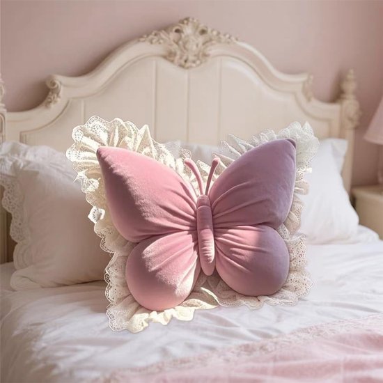 Roze vlinderkussen met kanten rand, op een wit bed.