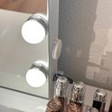 Detail van witte make-upspiegel met 2 LED lampen en 3 flacons.
