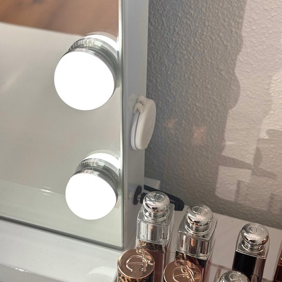 Detail van witte make-upspiegel met 2 LED lampen en 3 flacons.