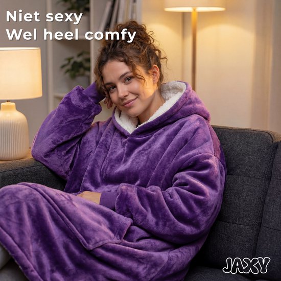 Een vrouw in een paarse, superzachte dekenhoodie, zittend op een bank, met de tekst 'Niet sexy, wel heel comfy'.