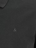 Close-up van een zwarte polo met geborduurd logo op de borst