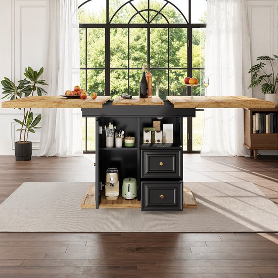 Houten tafel volledig uitgeschoven, met 4 stoelen (2 grijs, 2 wit). Donker onderstel met open kast met apparaten en potjes.