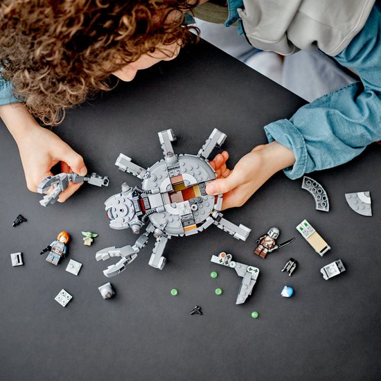 Kinderhanden bouwen een LEGO Spider Tank met losse onderdelen en minifiguren.