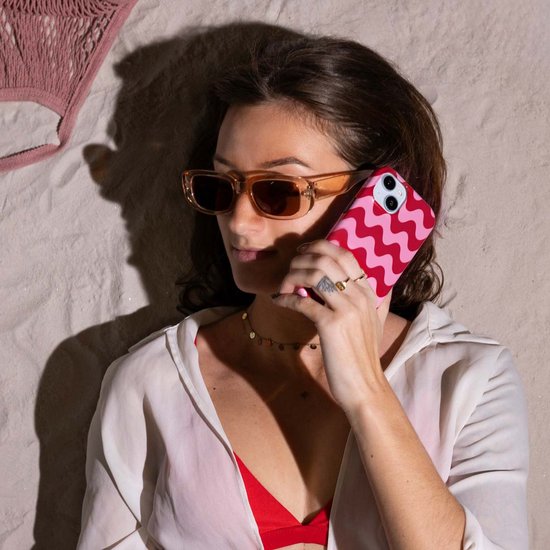 Een vrouw met zonnebril belt met een telefoon met hoesje met roze en rode golven.
