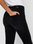 Zijaanzicht van een vrouw die een zwarte skinny jeans draagt, hand in de zak.