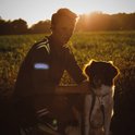 Jonge man met reflecterende Bee-Safe band op zijn arm, zittend naast een hond.
