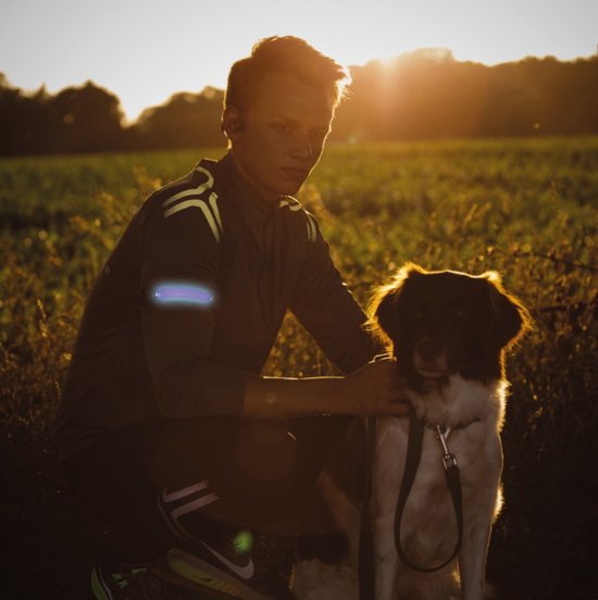 Jonge man met reflecterende Bee-Safe band op zijn arm, zittend naast een hond.