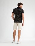 Achterkant van een man in beige shorts en zwart shirt met bloemenprint.