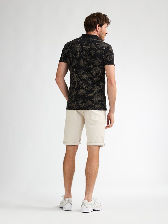 Achterkant van een man in beige shorts en zwart shirt met bloemenprint.