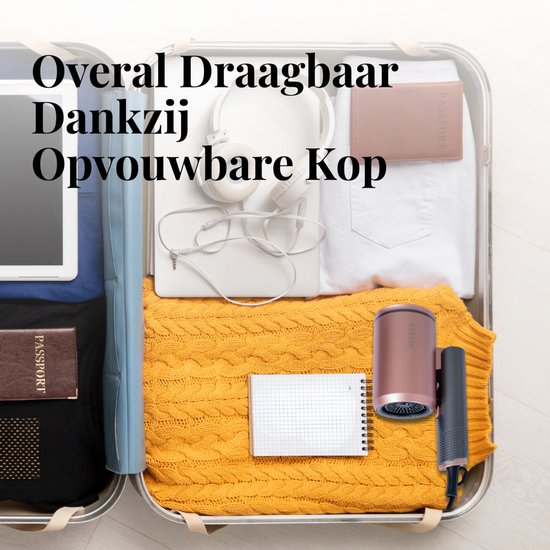 Rosegouden Beyeza haardroger opgevouwen in een koffer, naast paspoorten, koptelefoon en kleding. Compact voor reizen.