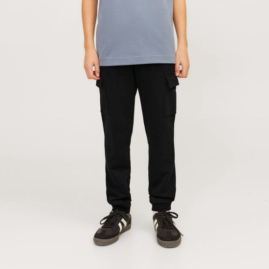 Jongens in een zwarte cargobroek en grijze t-shirt, staand.