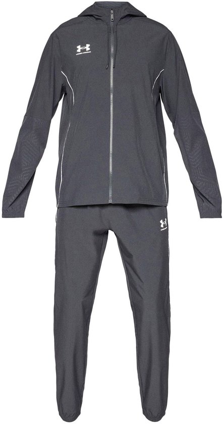 Grijs trainingspak bestaande uit een jas met capuchon en broek, met witte biezen en Under Armour logo's.