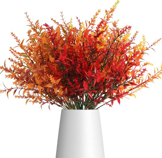 Un bouquet de branches artificielles d'automne aux feuilles oranges, rouges et jaunes dans un vase blanc.