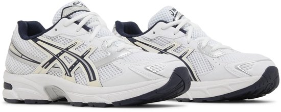 Witte sneakers met donkerblauwe en zilveren accenten, ASICS-logo op de zijkant.