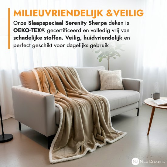 Een taupe plaid met witte sherpa voering, gedrapeerd over een grijze bank in een woonkamer. Tekst "MILIEUVRIENDELIJK & VEILIG" en "OEKO-TEX®".