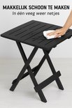 Zwarte inklapbare tafel wordt schoongemaakt met een wit doekje.