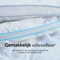 Détail d'une couette blanche avec passepoil bleu et une structure en filet. Texte : 'Facilement lavable'.