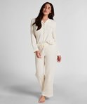 Model in een crèmewitte pyjamaset met lange mouwen en knoopsluiting.