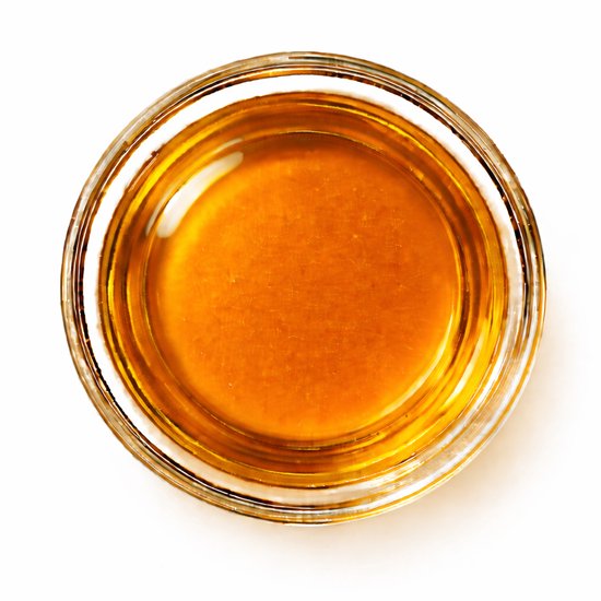 Gouden olie in een glazen schaaltje, van bovenaf gezien.