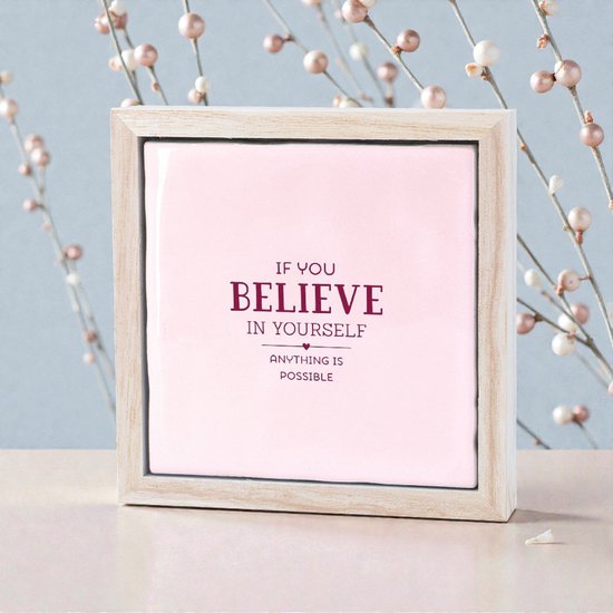 Lichtroze tegeltje met tekst 'IF YOU BELIEVE IN YOURSELF ANYTHING IS POSSIBLE' in houten lijst, met decoratieve takjes.