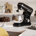 Zwarte keukenmachine op aanrecht naast een chocoladetaart.