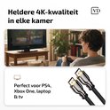 Onderkant van een vrouw kijkt tv met afstandsbediening. HDMI-kabels met vergulde connectoren.