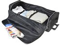 Zwarte reistas open met kleding, tijdschriften en lader.