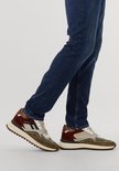 Close-up van modelbenen in blauwe jeans met olijfgroene en bordeauxrode Floris van Bommel sneakers.