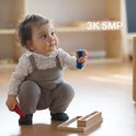 Een baby in een tuinbroek zit op de grond, met de tekst '3K 5MP' erbij.
