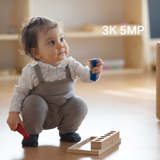 Een baby in een tuinbroek zit op de grond, met de tekst '3K 5MP' erbij.