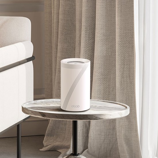 Witte Deco BE65 router met grijze lijnen, staand op een marmeren bijzettafel naast gordijnen.