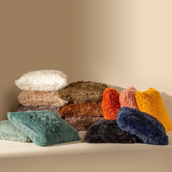 Une pile de coussins fluffy dans des couleurs telles que blanc, marron, orange, rose, jaune, vert, noir et bleu.