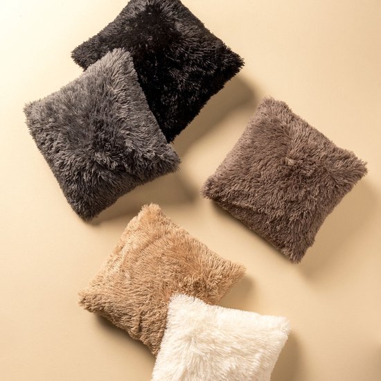 Cinq coussins fluffy noirs, gris, marron, beige et blancs sont disposés.