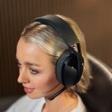 Een jonge vrouw met blond haar draagt een zwarte Logitech G gaming headset met stoffen hoofdband.