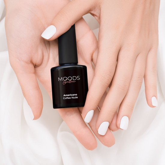 Houdt een flesje 'Americano Coffee Nude' nagellak vast. De nagels zijn wit gelakt.