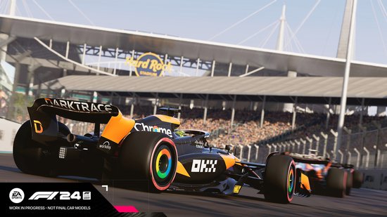Een oranje en zwarte Formule 1 auto met regenboog velgen racet voor een stadion.