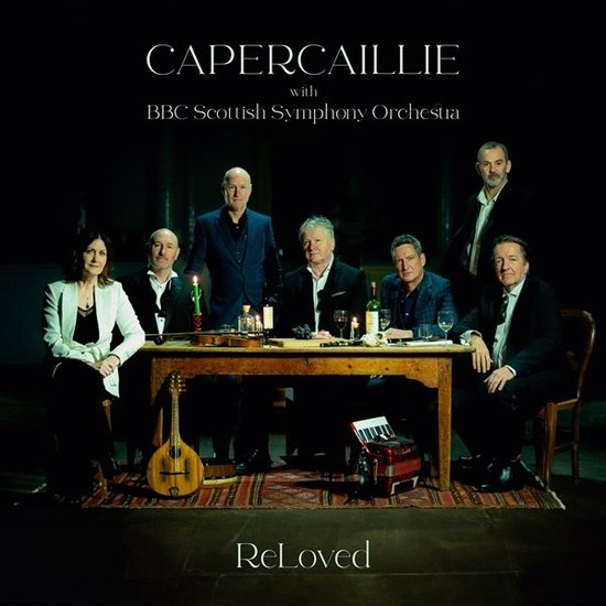 Capercaillie met BBC Scottish Symphony Orchestra op het album 'ReLoved'. Groepsfoto van 8 personen rond een tafel.