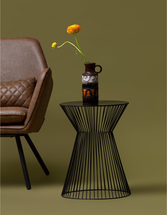 Zwarte bijzettafel met een vaas met een gele bloem, naast een bruine fauteuil.