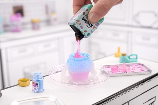 Een hand giet roze vloeistof in een gegradueerde blauw-roze pot met armen. Blauwe glitter staat ernaast.