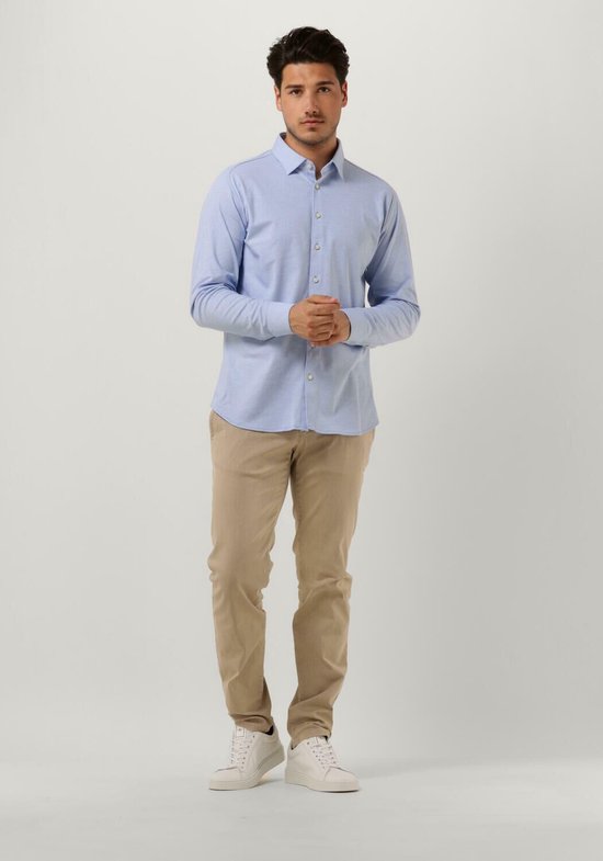 Homme portant une chemise bleu clair et un pantalon beige.