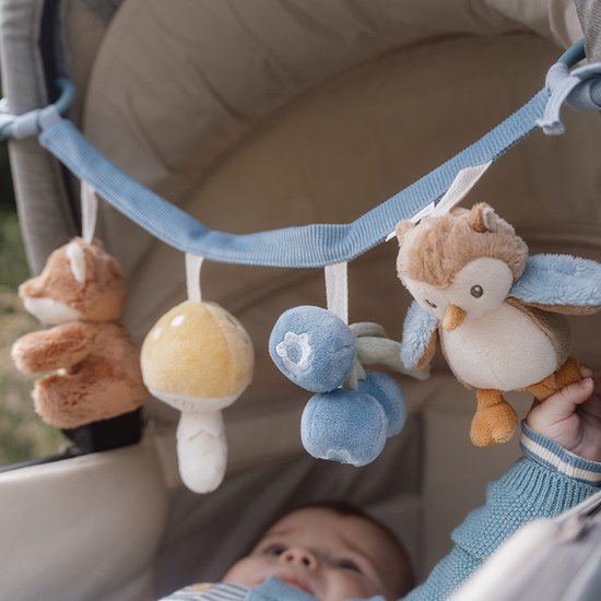 Baby speelt met kinderwagenhanger met vos, paddenstoel, bosbessen en uil.