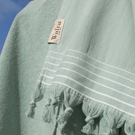 Detail van een jadegroene hamamdoek met witte strepen, kwastjes en Walra label. Gerecycled katoen.