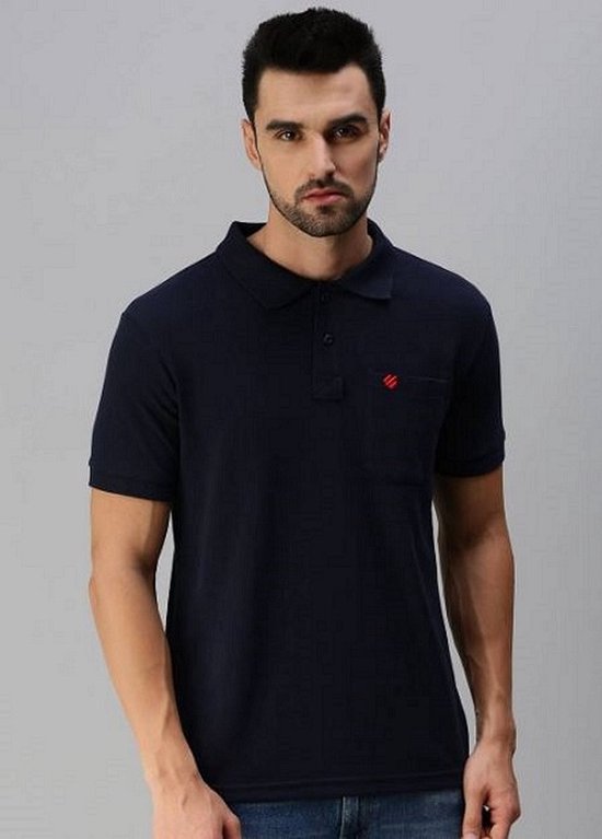 Homme en polo bleu marine avec poche poitrine et logo rouge. Fond gris.