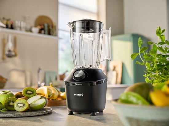 Zwarte Philips blender op een aanrecht met fruit en groenten.