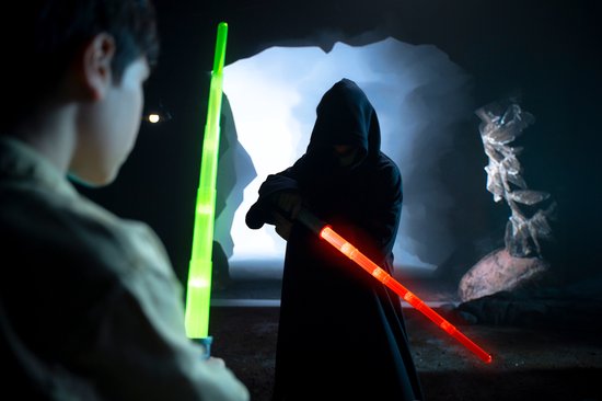 Un garçon et une silhouette en manteau noir avec des sabres laser verts et rouges.