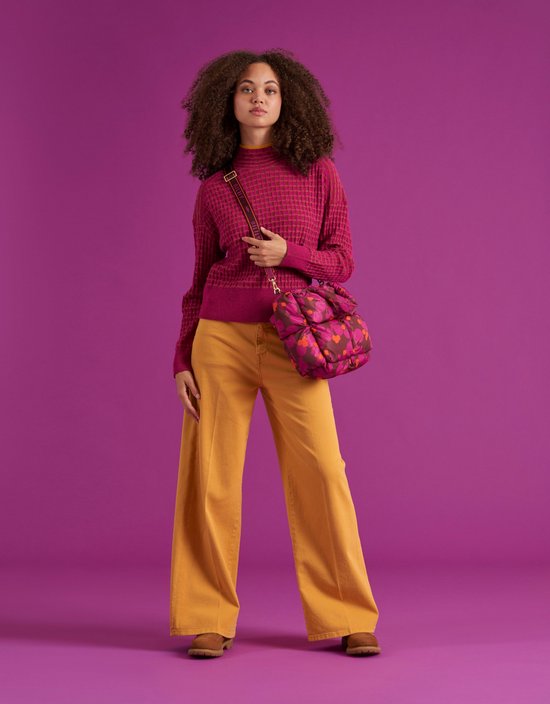 Model met een puffy handtas met paarse en oranje bloemenprint, gedragen met een roze trui en gele broek.