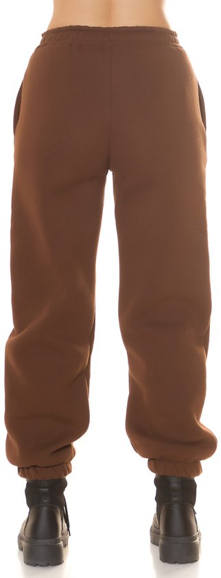 Achterkant van een bruine joggingbroek met hoge taille, gedragen met zwarte laarzen.