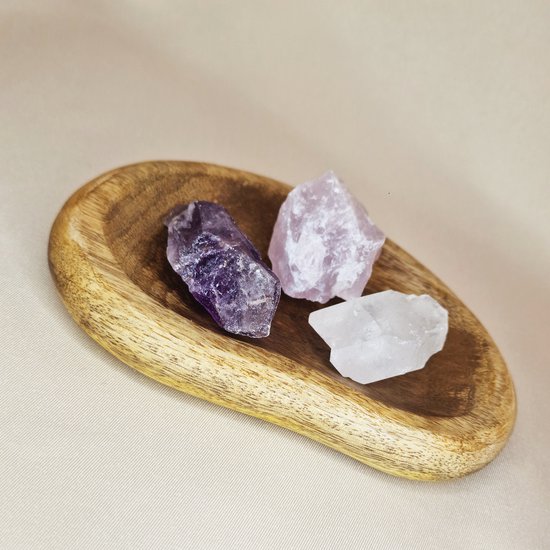 Bol en bois avec trois pierres brutes: violet (améthyste), rose pâle (quartz rose) et clair (cristal de roche).